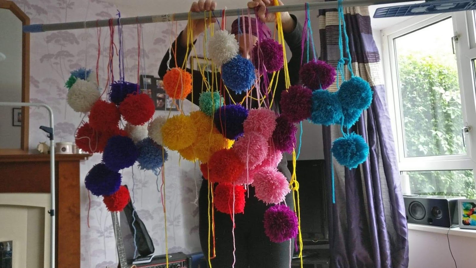 Tracy with many pompoms hanging from a broom handle